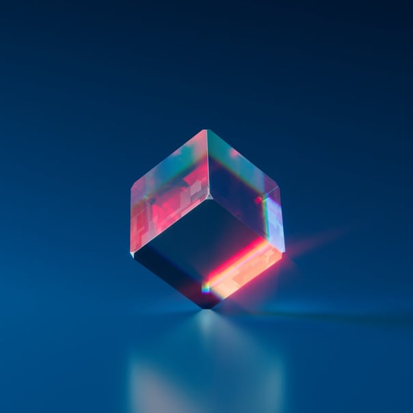 Image of a cube made by glass, standing up by one of it's corner and reflecting a red/orange light, like the light of the sun. 